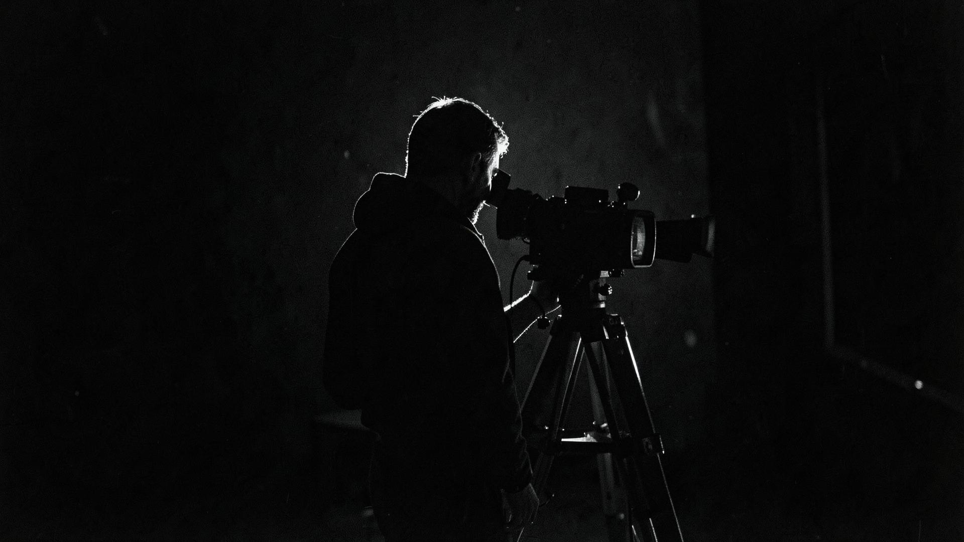Cinematographer behind a cinema camera on a dark set